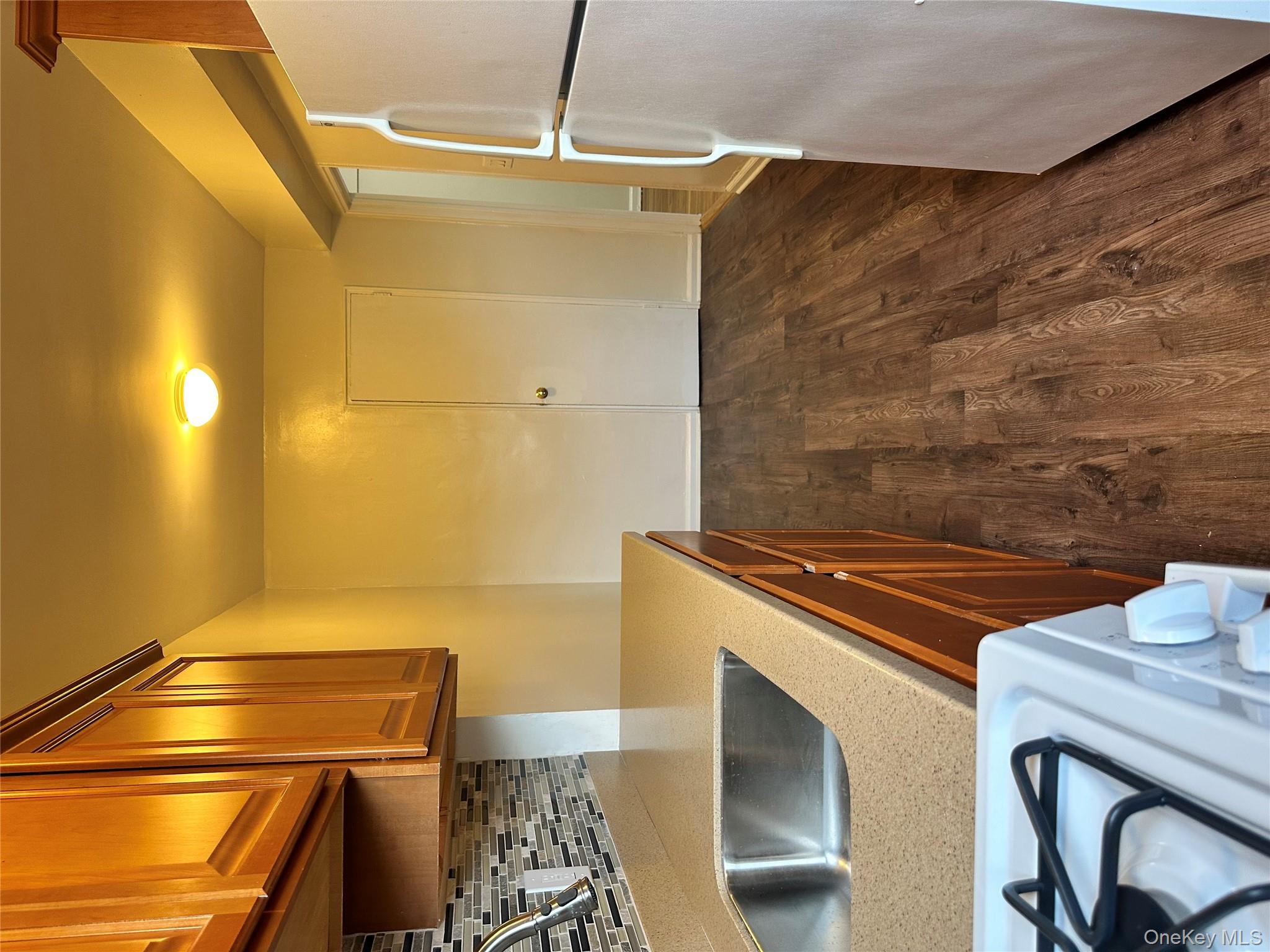 150-25 72nd Road, Unit 1J Queens, NY 11367 - Photo 4 of 14 a kitchen with kitchen island a stove a sink and a refrigerator with wooden floor