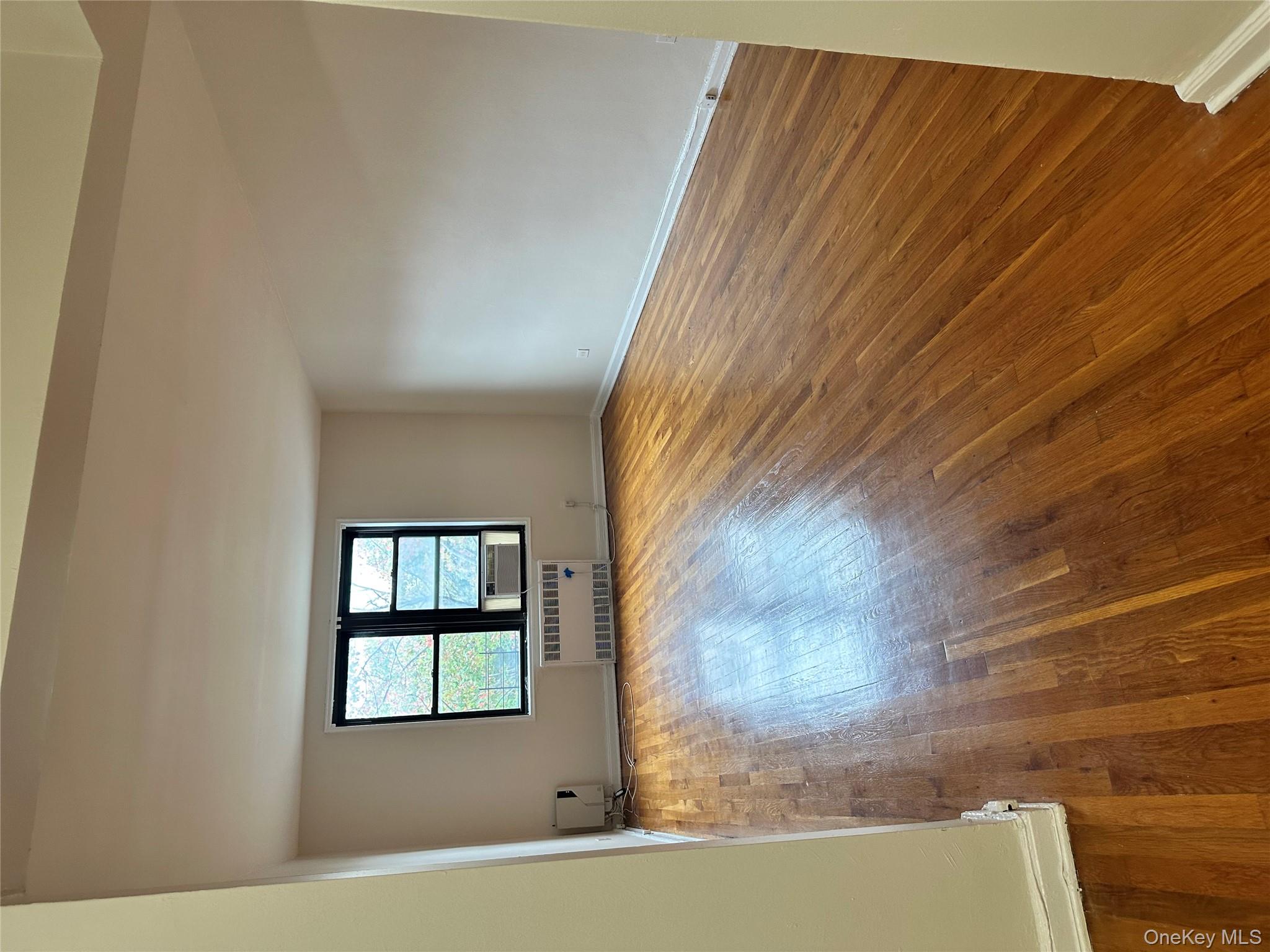 150-25 72nd Road, Unit 1J Queens, NY 11367 - Photo 5 of 14 wooden floor in an empty room with a window