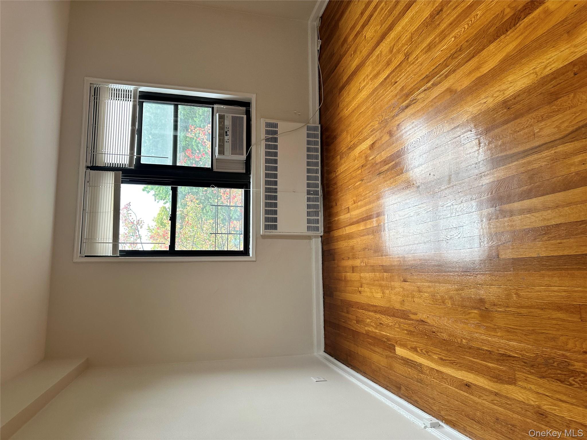 150-25 72nd Road, Unit 1J Queens, NY 11367 - Photo 7 of 14 a view of an empty room with wooden floor and a window
