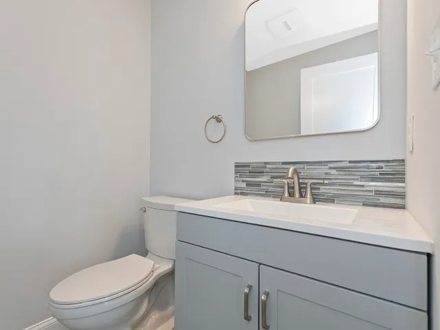 a bathroom with a toilet sink vanity and mirror