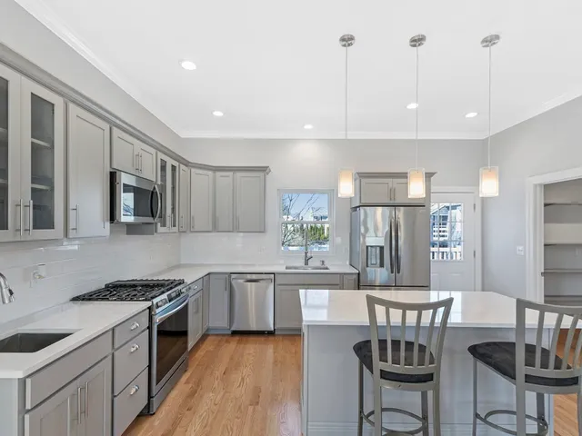 a kitchen with stainless steel appliances granite countertop a stove top oven a sink a dining table and chairs