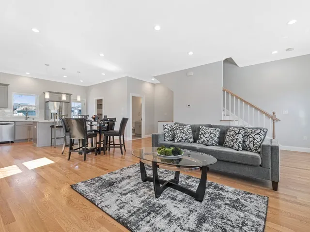a living room with furniture and a dining table with wooden floor