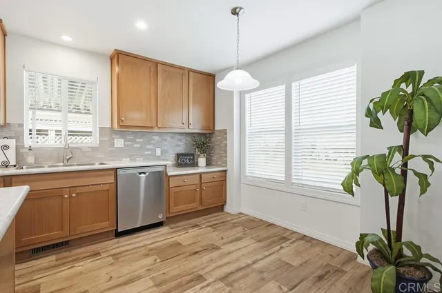 a kitchen with stainless steel appliances granite countertop a sink a window and wooden floor
