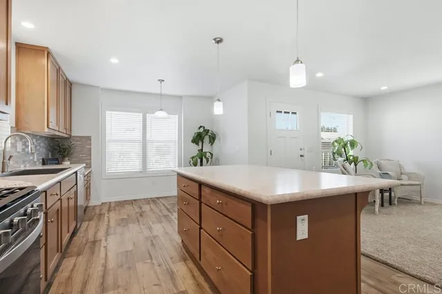 a kitchen with kitchen island a counter top space a sink stainless steel appliances and cabinets
