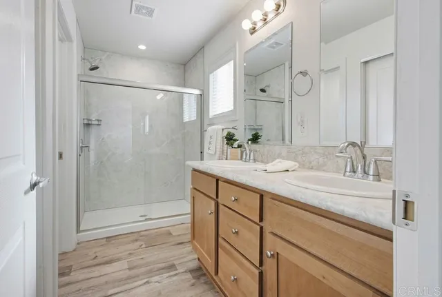 a bathroom with a shower sink vanity granite and mirror