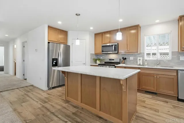 a kitchen with stainless steel appliances granite countertop a refrigerator a sink dishwasher a stove and white cabinets with wooden floor