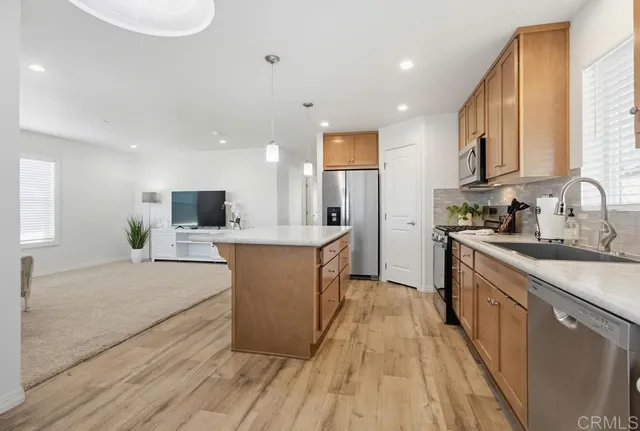 a large kitchen with stainless steel appliances kitchen island granite countertop a sink and a stove top oven with wooden floor