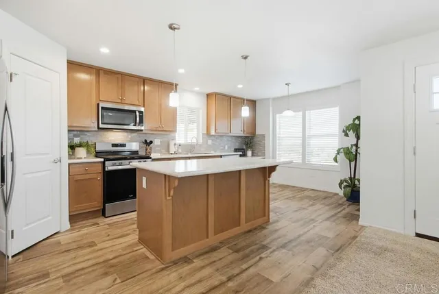 a kitchen with kitchen island granite countertop a sink cabinets and stainless steel appliances