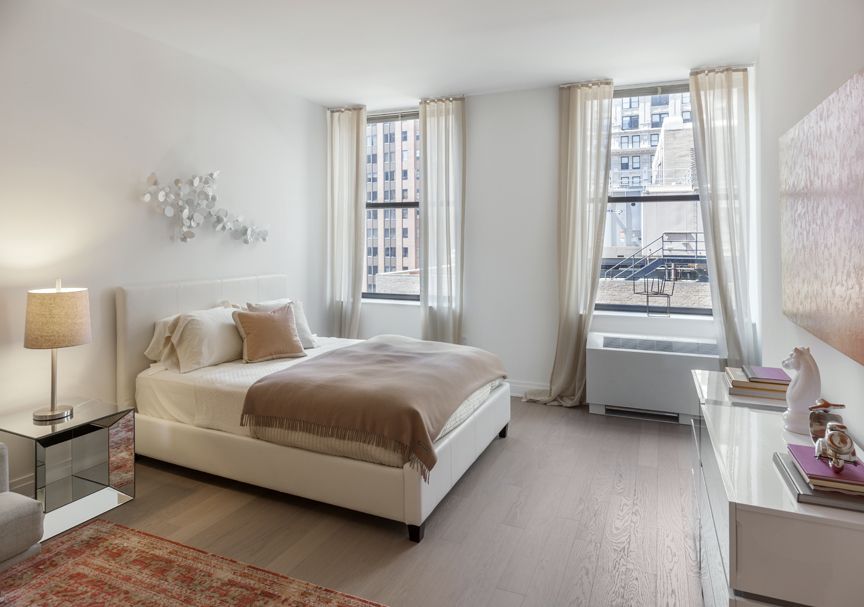 70 Pine Street, Unit 1802 Manhattan, NY 10005 - Photo 7 of 27 a spacious bedroom with a bed and a window