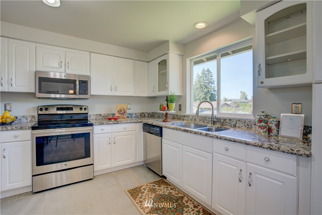2103 Southeast 21st Street Renton, WA 98055 - Photo 9 of 23 a kitchen with granite countertop a sink stainless steel appliances and white cabinets