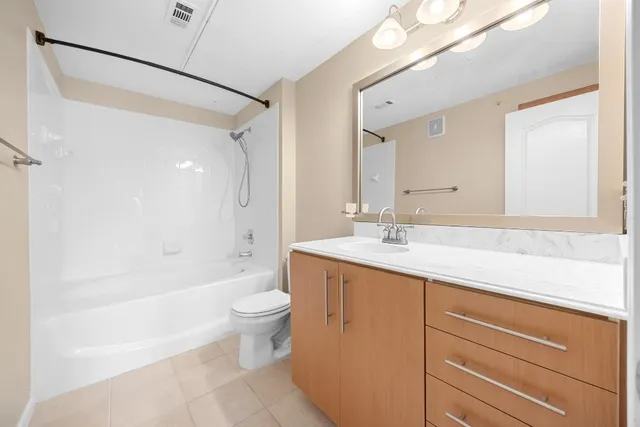 an empty room with chandelier fan and windows