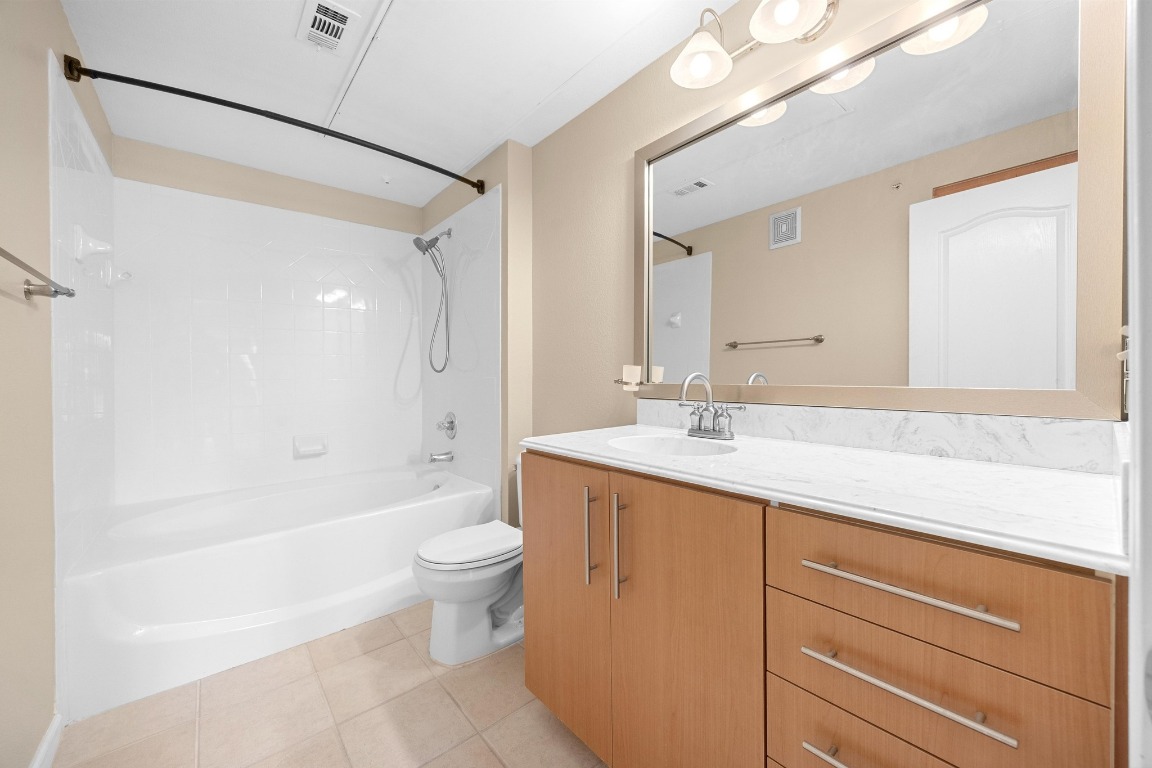 11203 Ranch Road 2222, Unit 1105 Austin, TX 78730 - Photo 14 of 35 a bathroom with a granite countertop sink a toilet a mirror and bathtub