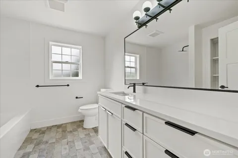 a bathroom with a granite countertop sink a toilet and a mirror