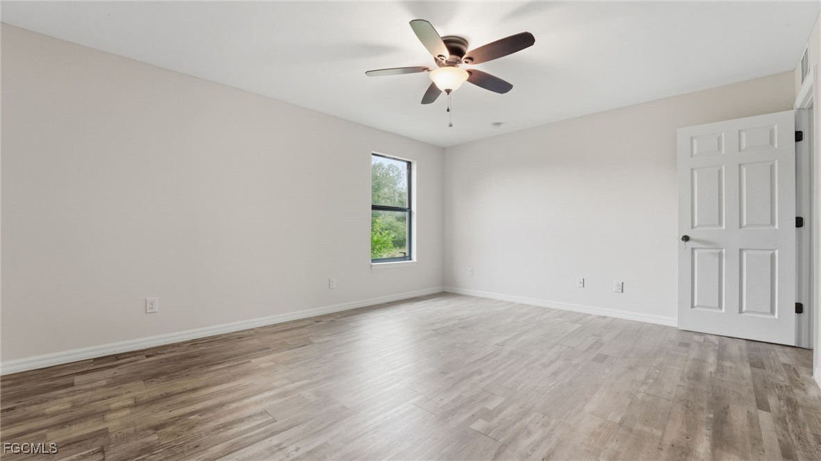 2701 East 18th Street Lehigh Acres, FL 33972 - Photo 4 of 24 an empty room with wooden floor and windows