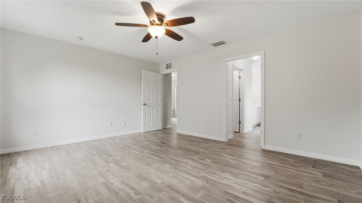 2701 East 18th Street Lehigh Acres, FL 33972 - Photo 5 of 24 an empty room with wooden floor and ceiling fan