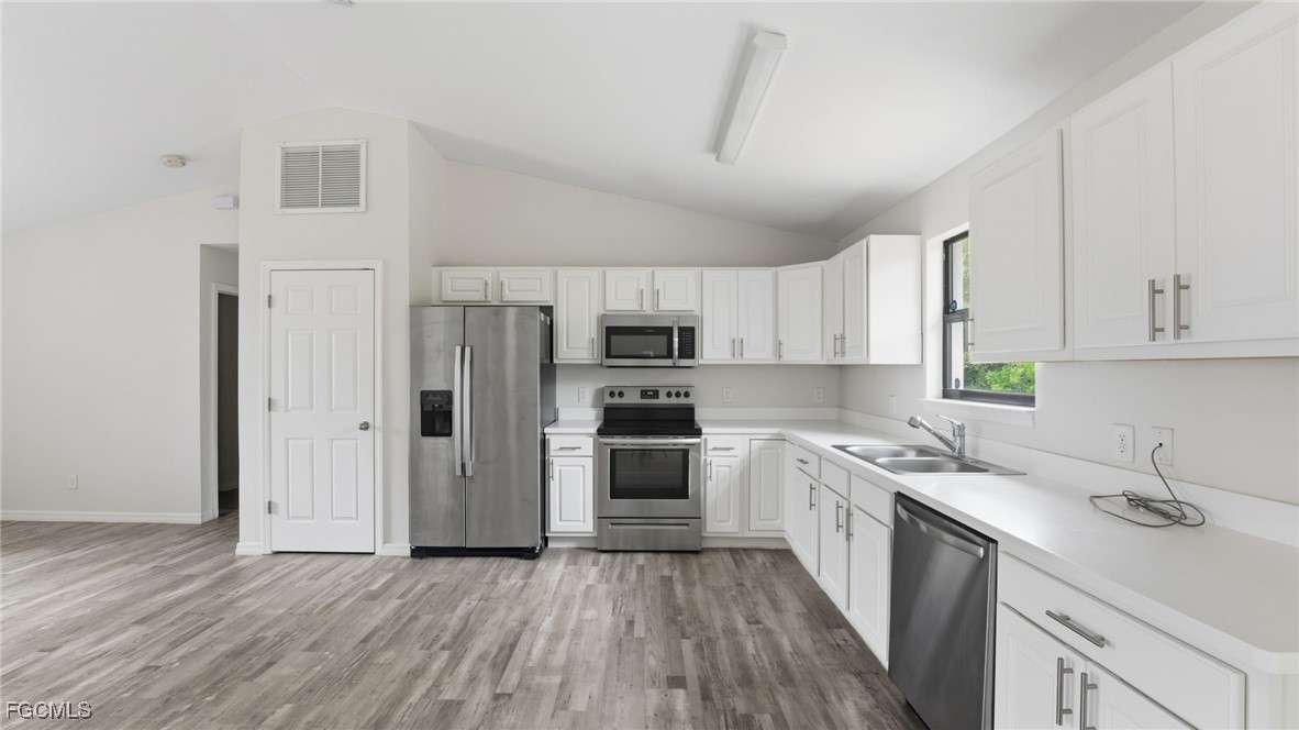 2701 East 18th Street Lehigh Acres, FL 33972 - Photo 10 of 24 a kitchen with wooden floors and stainless steel appliances