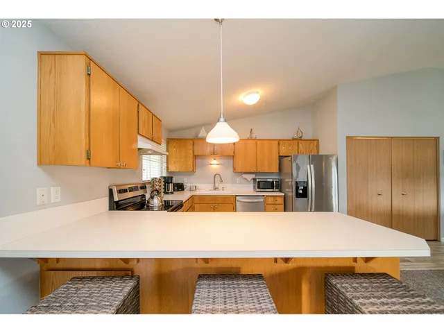 a kitchen with kitchen island a stove a sink a refrigerator and cabinets