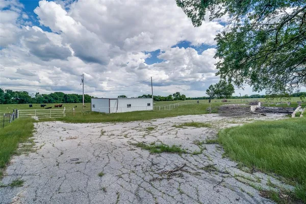 a view of a road with a big yard and a large tree