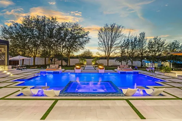 a view of swimming pool with chairs and trees