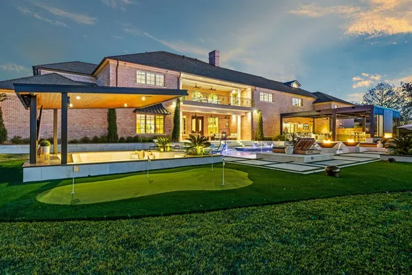 a view of swimming pool with lawn chairs and large trees