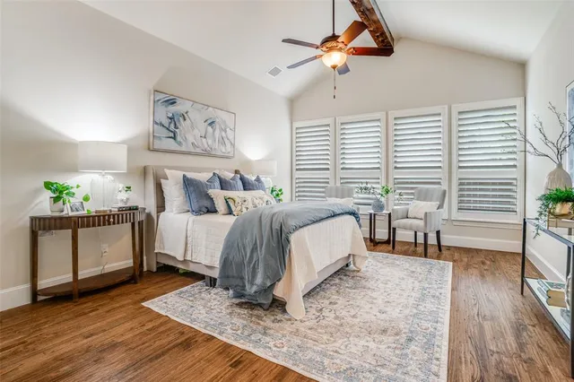 a spacious bedroom with a bed a couch and potted plant on the wooden floor