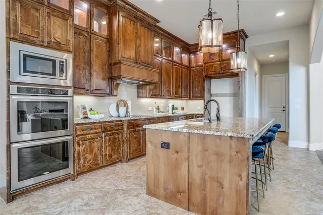 a kitchen with stainless steel appliances granite countertop a stove top oven a sink dishwasher a dining table and chairs with wooden floor