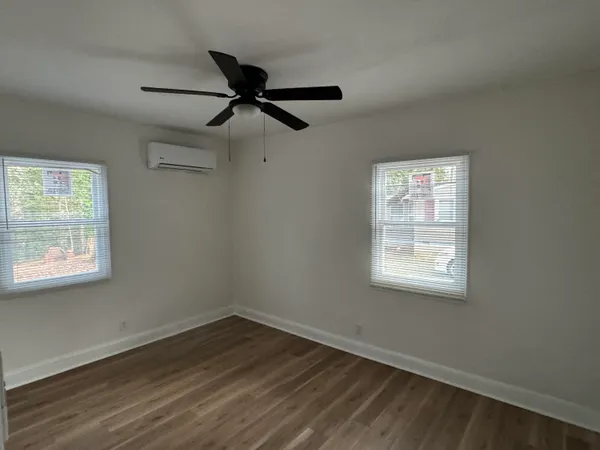 a view of an empty room with wooden floor and a window