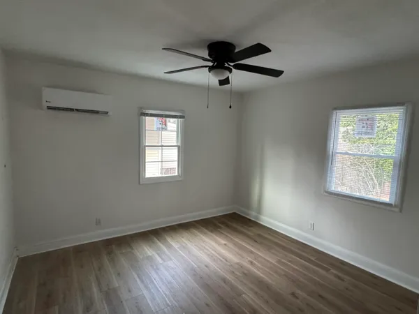 a view of an empty room with wooden floor and a window