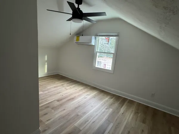 an empty room with wooden floor fan and windows