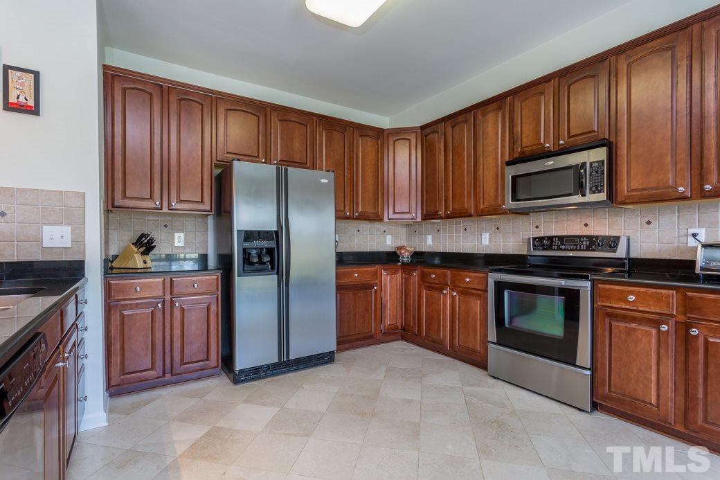 4357 Karlbrook Lane Raleigh, NC 27616 - Photo 12 of 25 a kitchen with stainless steel appliances granite countertop wooden cabinets a stove top oven a sink and dishwasher
