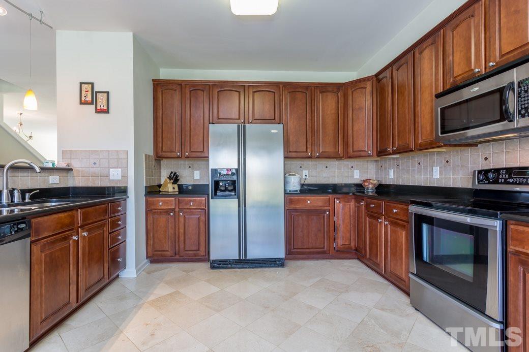 4357 Karlbrook Lane Raleigh, NC 27616 - Photo 13 of 25 a kitchen with stainless steel appliances granite countertop wooden cabinets a stove a sink and a refrigerator