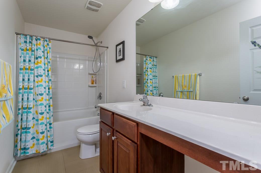 4357 Karlbrook Lane Raleigh, NC 27616 - Photo 17 of 25 a bathroom with a granite countertop sink a toilet a shower curtain and a bath tub