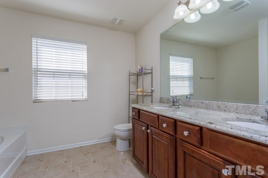 4357 Karlbrook Lane Raleigh, NC 27616 - Photo 22 of 25 a bathroom with a granite countertop sink a toilet and mirror