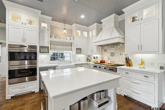 a large kitchen with stainless steel appliances kitchen island granite countertop a lot of counter space and a wooden floor