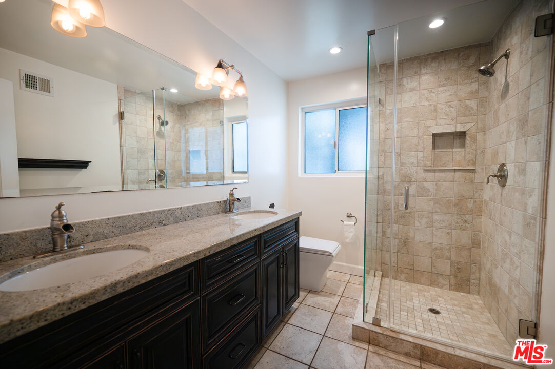 503 North Greencraig Road Los Angeles, CA 90049 - Photo 16 of 59 a bathroom with a granite countertop sink a large mirror and shower