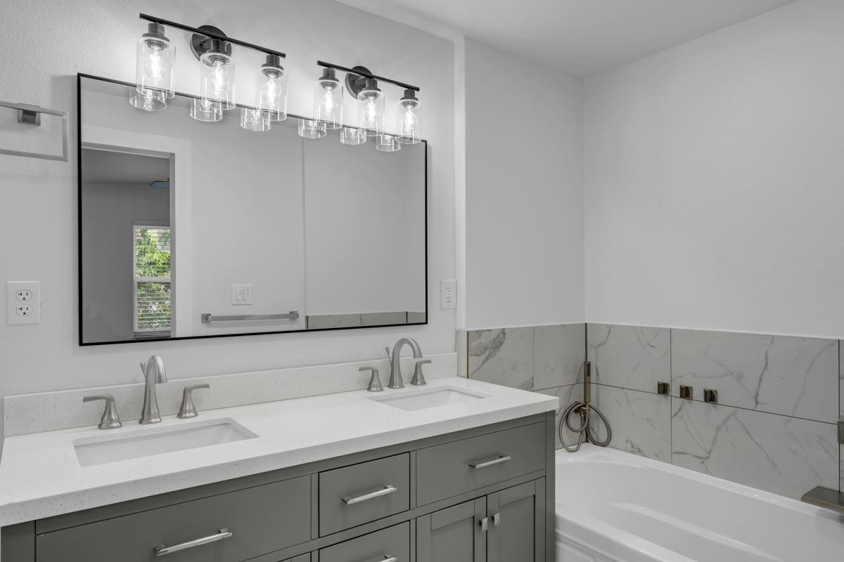 407 East Kerr Street Burnet, TX 78611 - Photo 12 of 21 a bathroom with a granite countertop sink mirror and a bathtub