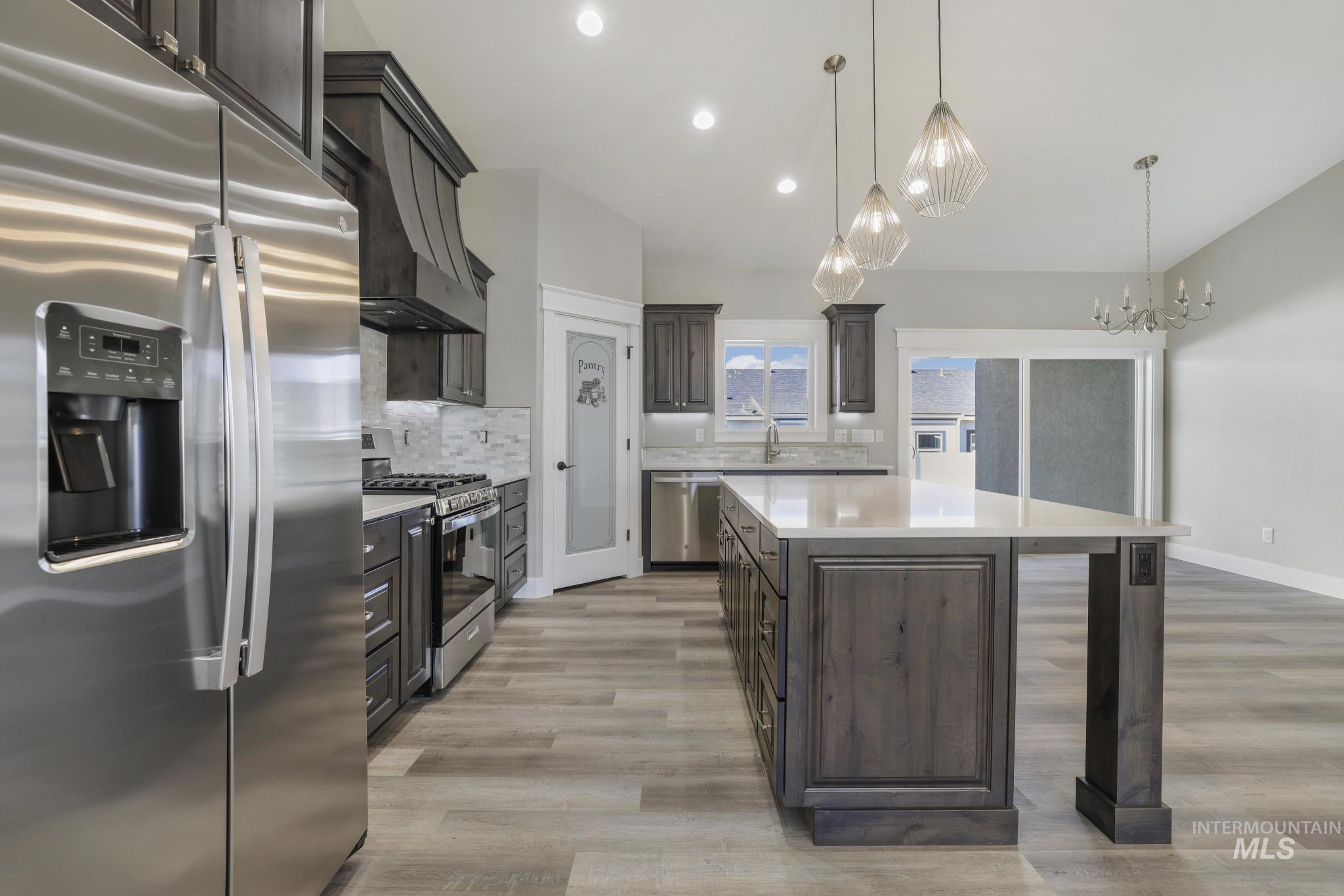 298 Sandi Road Twin Falls, ID 83301 - Photo 5 of 24 Gourmet kitchen with stainless steel appliances, dark wood cabinetry, white stone countertops, and a large central island