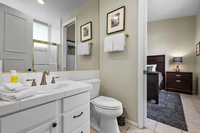 a spacious bathroom with a granite countertop sink a toilet a mirror and shower