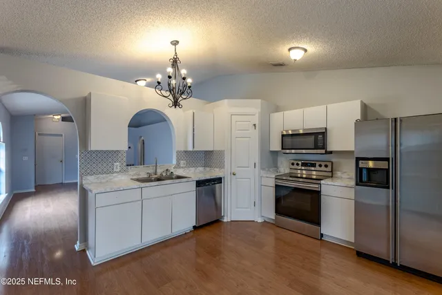 a kitchen with stainless steel appliances granite countertop a sink a stove a refrigerator cabinets and a dining table