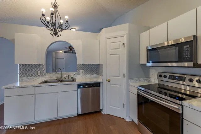 a kitchen with appliances a sink and cabinets