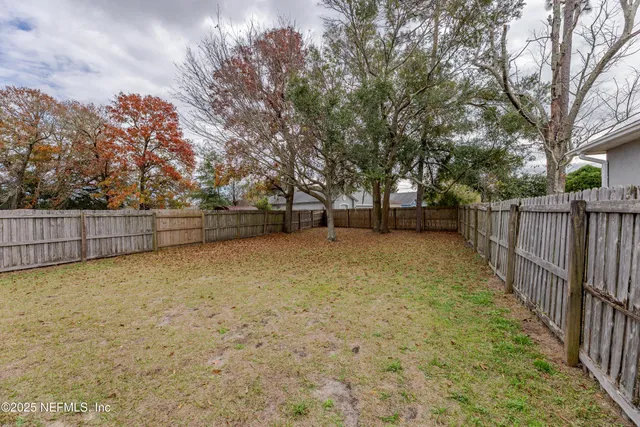 a view of backyard with wooden fence