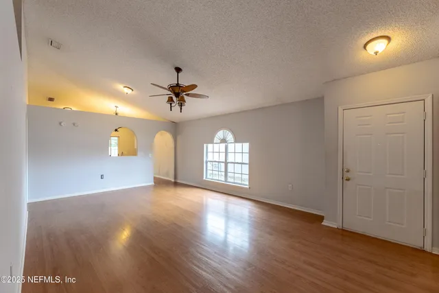 a view of an empty room with a window and wooden floor