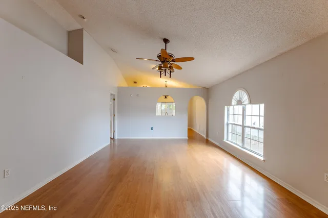 a view of empty room with wooden floor and fan