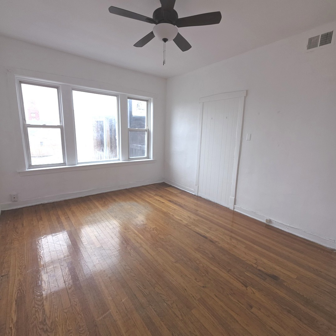 1248 North Spaulding Avenue, Unit 2 Chicago, IL 60651 - Photo 7 of 12 an empty room with wooden floor chandelier fan and windows