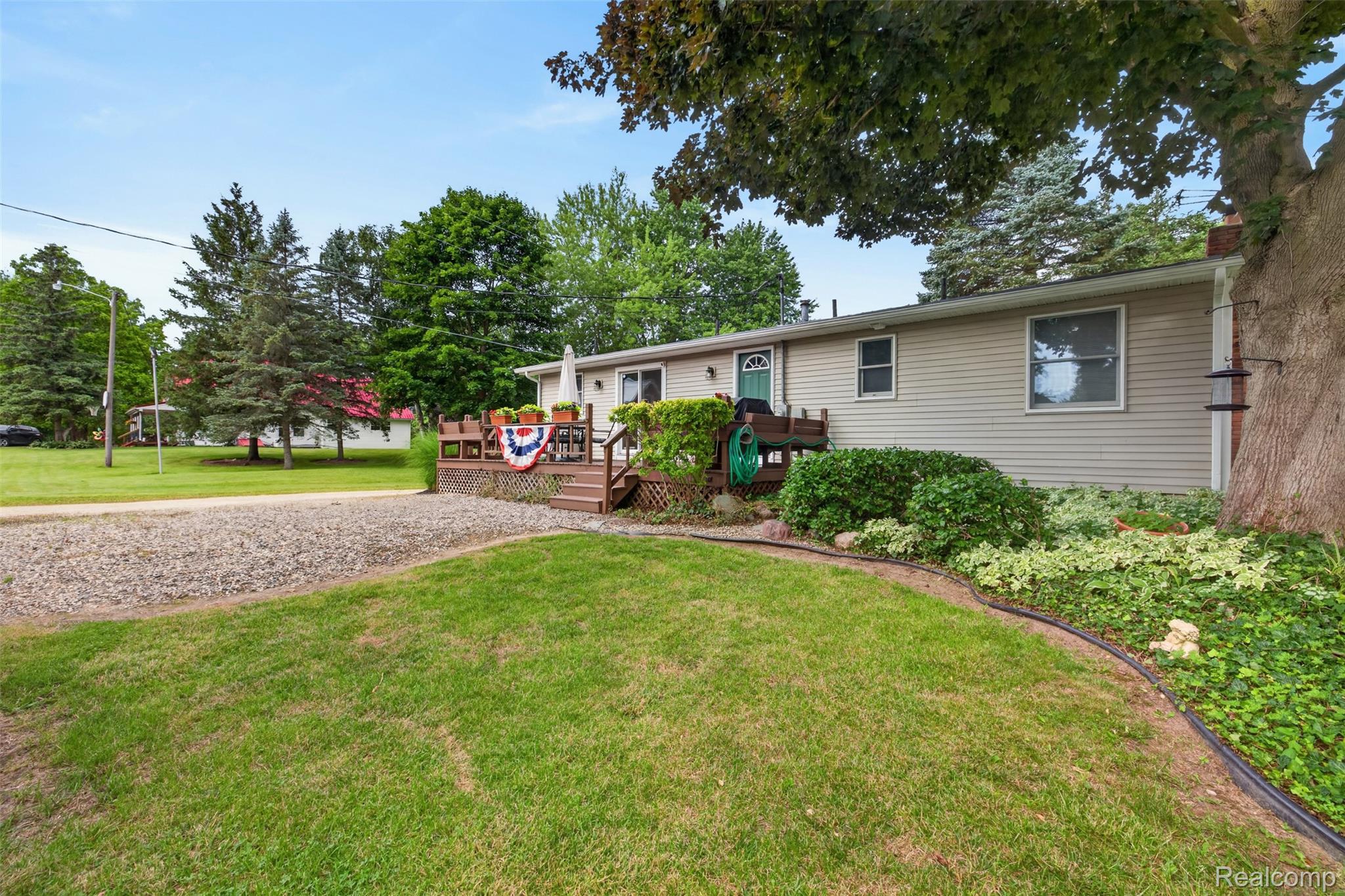5977 Anglers Road Ortonville, MI 48462 - Photo 57 of 63 Ranch-style residence featuring light-colored siding, a front entry deck with railings, and a gravel driveway