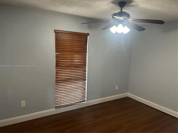 a view of empty room with wooden floor and chandelier
