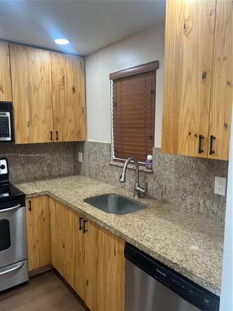 a kitchen with granite countertop a sink a stove and cabinets