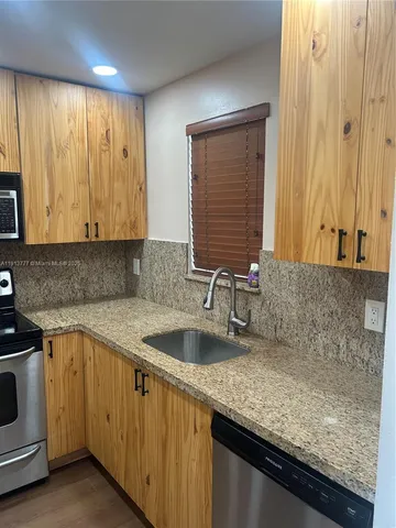 a kitchen with granite countertop a sink a stove and cabinets