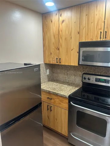a kitchen with granite countertop cabinets stainless steel appliances and a counter space