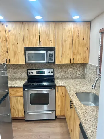 a kitchen with granite countertop a stove top oven microwave and refrigerator